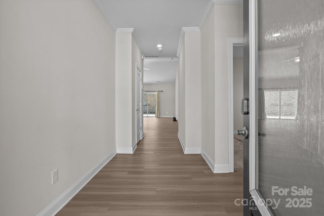 hall featuring baseboards, plenty of natural light, wood finished floors, and crown molding