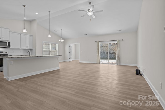 kitchen featuring white cabinets, an island with sink, open floor plan, light stone countertops, and stainless steel appliances