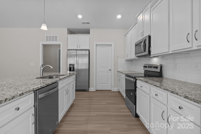 kitchen with visible vents, appliances with stainless steel finishes, a sink, and white cabinetry