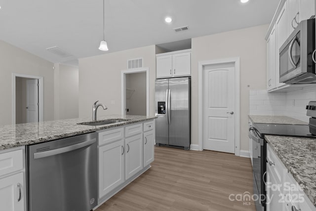 kitchen with stainless steel appliances, white cabinetry, a sink, and visible vents