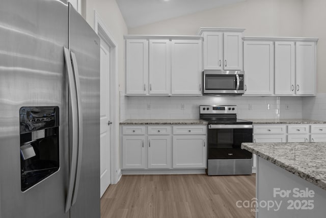 kitchen featuring backsplash, appliances with stainless steel finishes, light wood-style floors, white cabinetry, and vaulted ceiling