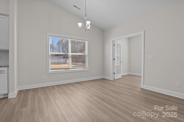 unfurnished dining area featuring lofted ceiling, visible vents, a notable chandelier, and light wood-style flooring