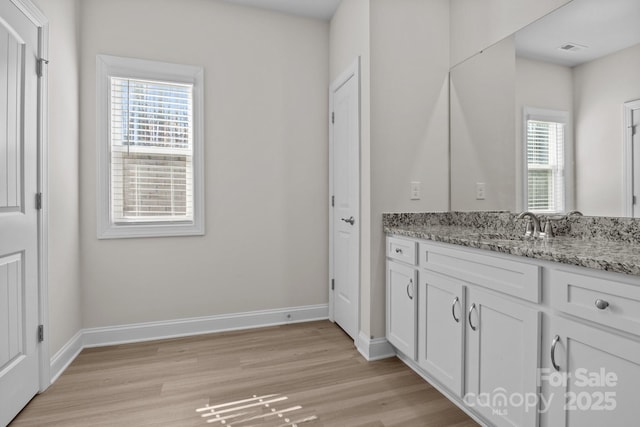 bathroom featuring visible vents, baseboards, wood finished floors, and vanity