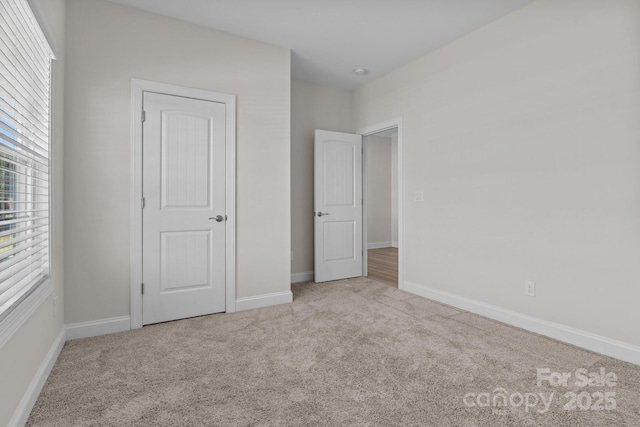 unfurnished bedroom featuring baseboards and light colored carpet