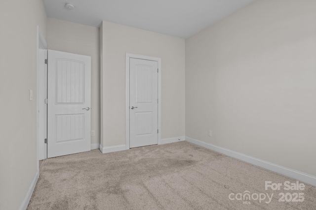 unfurnished bedroom with light colored carpet and baseboards