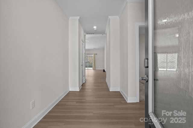 corridor featuring crown molding, baseboards, and wood finished floors