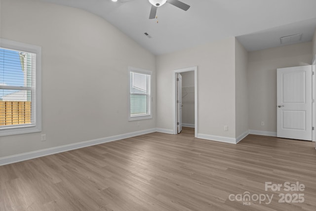 unfurnished bedroom with visible vents, vaulted ceiling, baseboards, a spacious closet, and light wood-style floors