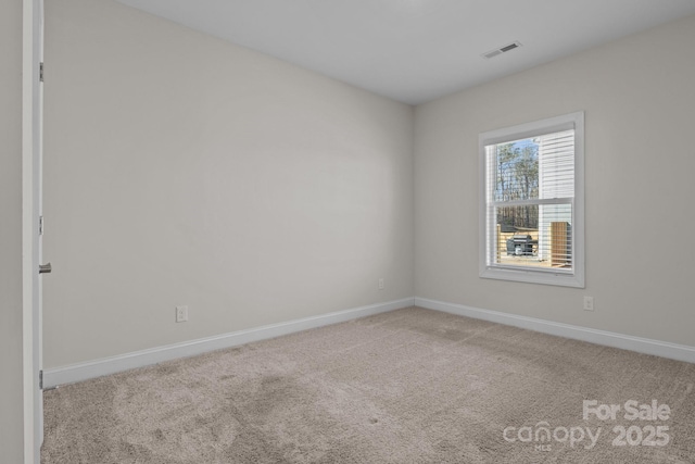 carpeted spare room with visible vents and baseboards