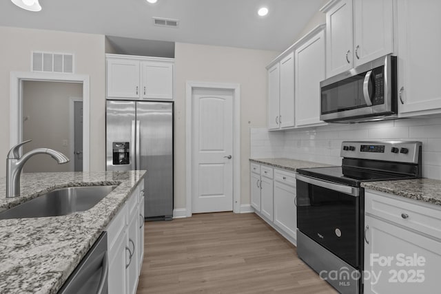 kitchen with visible vents, a sink, appliances with stainless steel finishes, and white cabinets