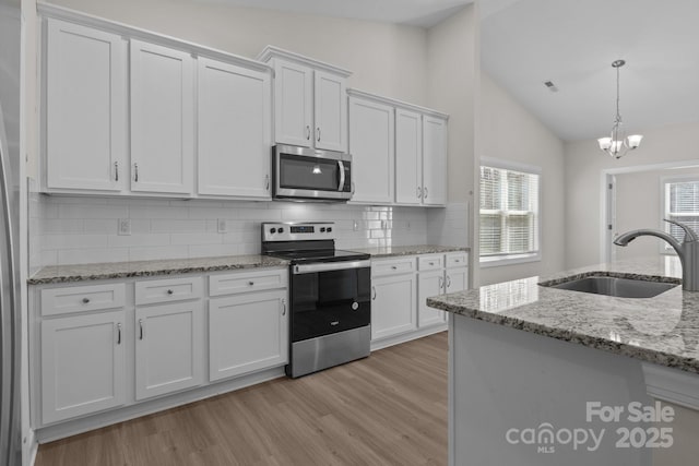 kitchen with a sink, appliances with stainless steel finishes, light wood-style floors, and vaulted ceiling