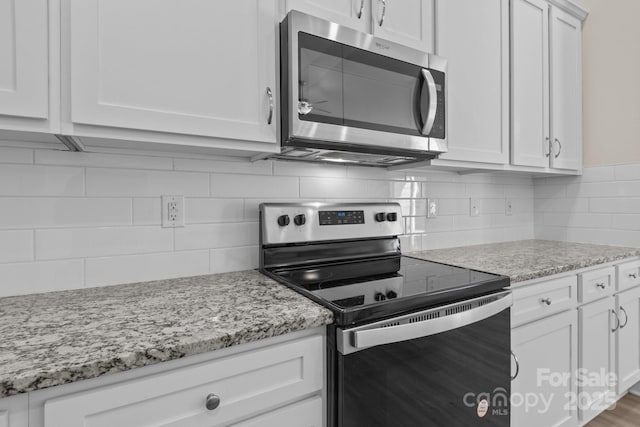 kitchen featuring light stone counters, decorative backsplash, appliances with stainless steel finishes, and white cabinets