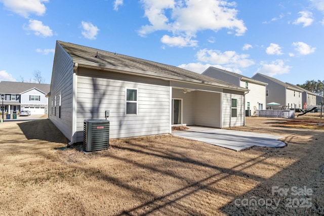 rear view of house with central air condition unit, a patio, a residential view, and a lawn