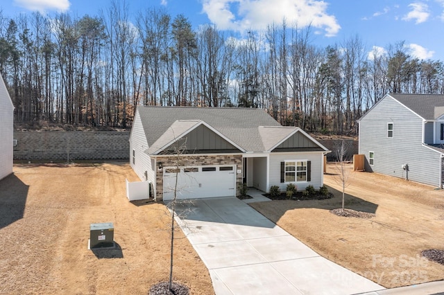 view of front facade with board and batten siding, roof with shingles, concrete driveway, an attached garage, and stone siding