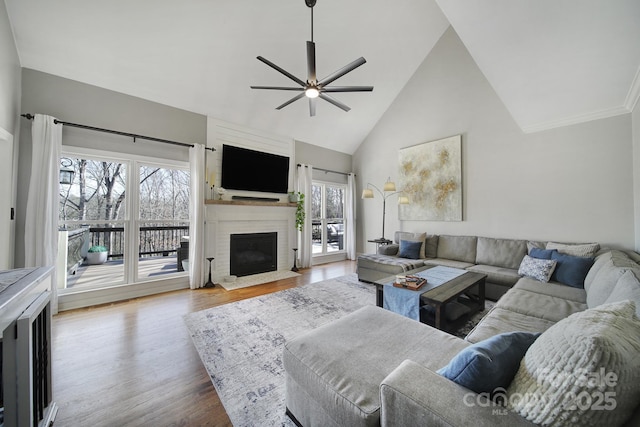 living area featuring a brick fireplace, high vaulted ceiling, ceiling fan, and wood finished floors