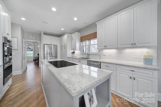 kitchen featuring decorative backsplash, white cabinets, appliances with stainless steel finishes, and a kitchen island