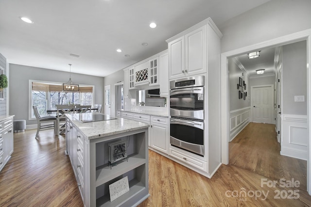 kitchen featuring open shelves, white cabinets, double oven, black electric stovetop, and a center island