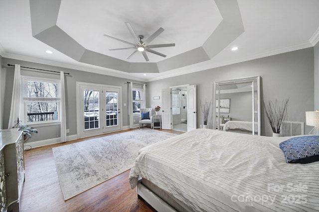 bedroom featuring crown molding, a raised ceiling, baseboards, and wood finished floors