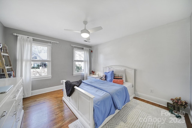 bedroom featuring visible vents, a ceiling fan, baseboards, and wood finished floors