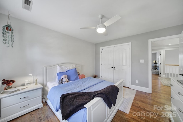 bedroom with visible vents, ceiling fan, baseboards, wood finished floors, and a closet