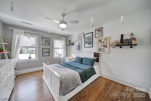 bedroom featuring visible vents, ceiling fan, baseboards, and wood finished floors