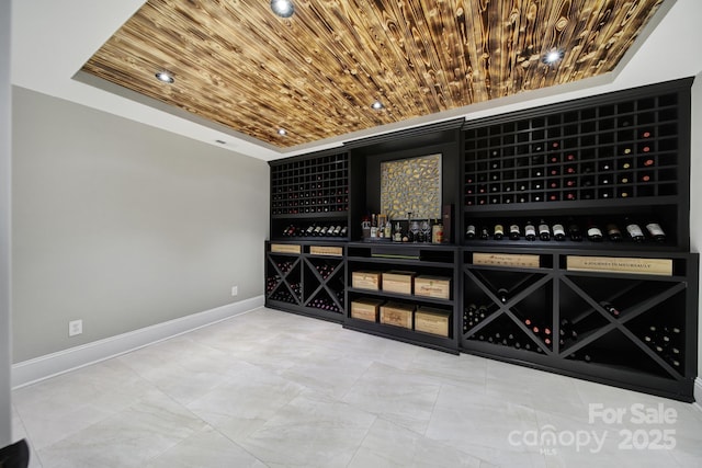 wine area featuring wooden ceiling, baseboards, and a tray ceiling