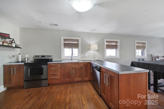 kitchen with visible vents, stainless steel counters, dark wood finished floors, stainless steel appliances, and a peninsula