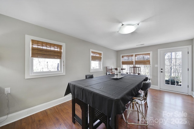 dining area featuring dark wood-type flooring and baseboards