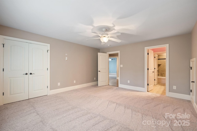 unfurnished bedroom with light colored carpet, connected bathroom, baseboards, and ceiling fan