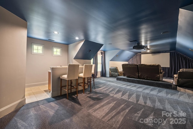 cinema room with light tile patterned floors, lofted ceiling, light colored carpet, visible vents, and baseboards