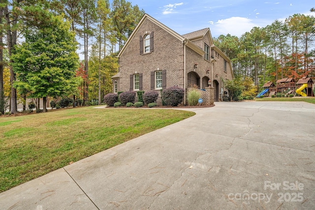 view of front of property with brick siding, a playground, and a front yard