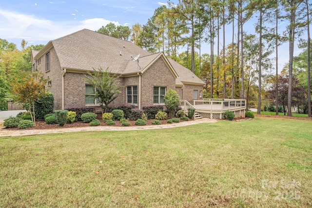 view of front of house with a deck, a front lawn, a shingled roof, and brick siding