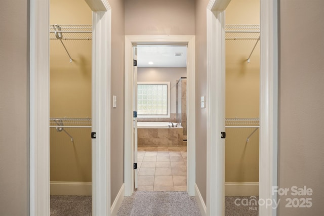 hall featuring light tile patterned floors and light colored carpet