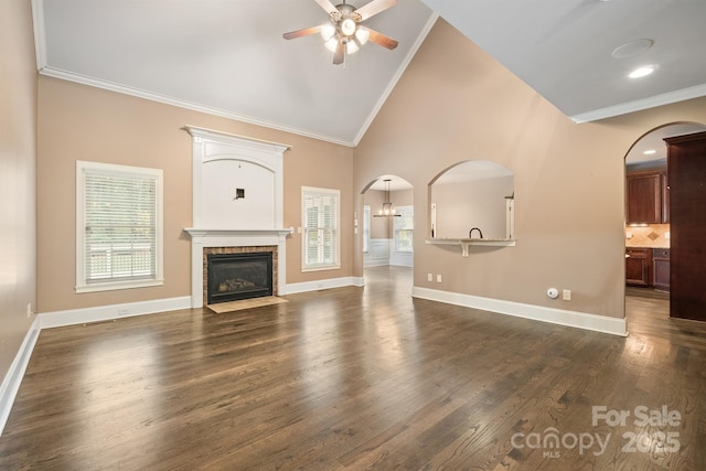 unfurnished living room featuring dark wood-style floors, arched walkways, a wealth of natural light, and crown molding