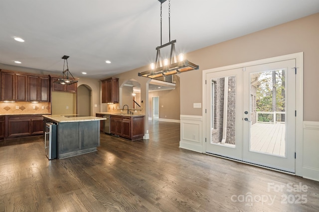 kitchen with arched walkways, dark wood-style flooring, french doors, pendant lighting, and a sink