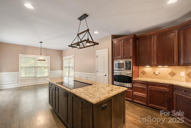 kitchen featuring light stone countertops, stainless steel appliances, backsplash, a center island, and pendant lighting