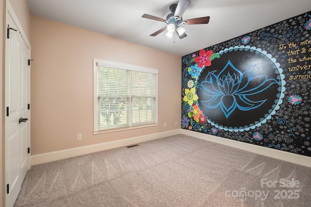 empty room with carpet floors, visible vents, ceiling fan, and baseboards