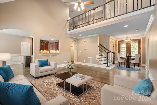 472 Barber Loop, Mooresville, NC 28117 - living area featuring stairs, arched walkways, wood finished floors, a ceiling fan, and a high ceiling