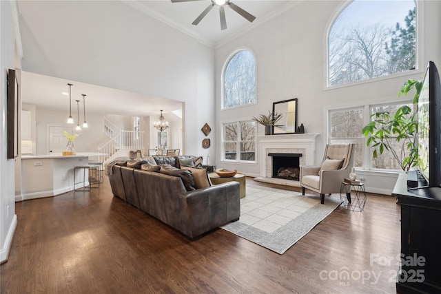 living room with a fireplace with raised hearth, ornamental molding, stairway, and wood finished floors