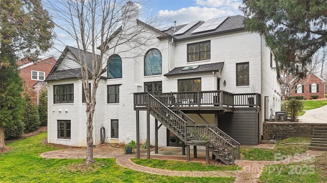 back of property featuring a yard, a wooden deck, stairway, and brick siding