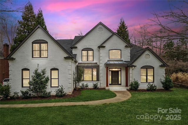 french country inspired facade with a front lawn and brick siding