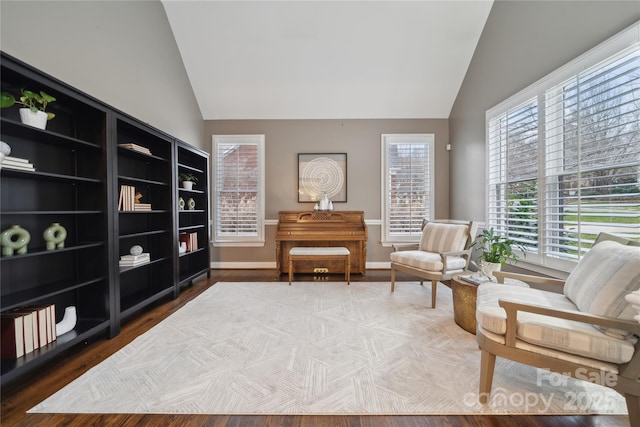 living area featuring lofted ceiling, baseboards, and wood finished floors