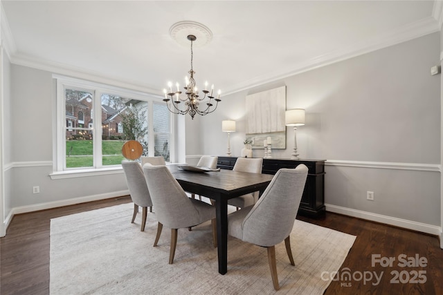 dining room featuring dark wood-type flooring, a chandelier, crown molding, and baseboards