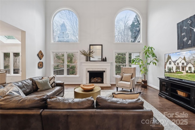 living area with a healthy amount of sunlight, a fireplace with raised hearth, and a towering ceiling