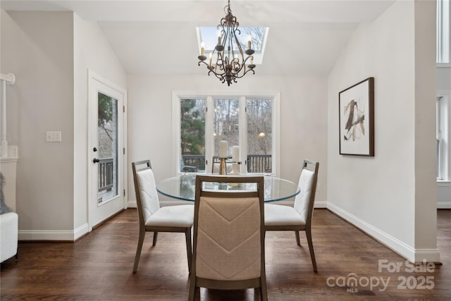 dining area with dark wood-style flooring, a notable chandelier, vaulted ceiling, and baseboards