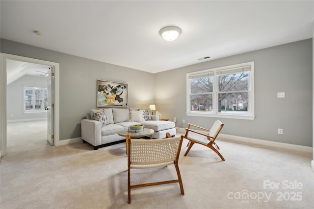 living area with baseboards, visible vents, and light colored carpet