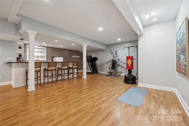 workout area with baseboards, light wood-style floors, recessed lighting, and ornate columns