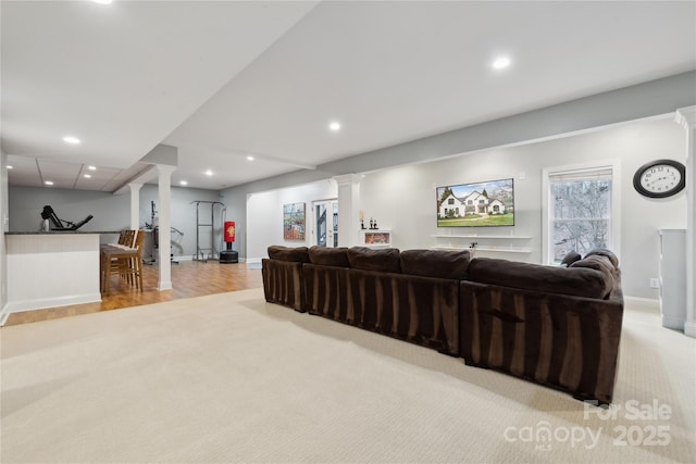 living area featuring light carpet, baseboards, light wood-style flooring, ornate columns, and recessed lighting