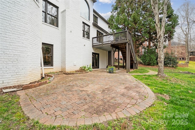 exterior space with a deck, a patio, brick siding, a yard, and stairway