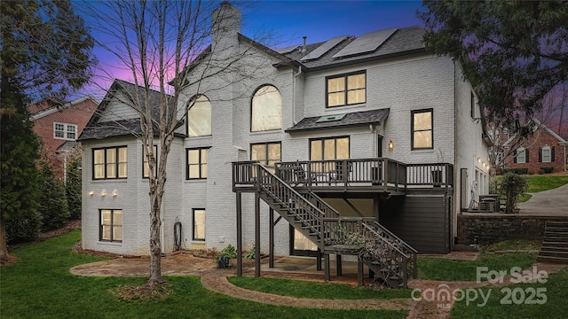 back of house featuring a deck, a yard, brick siding, and stairway