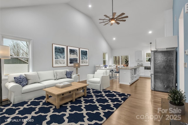 living area featuring recessed lighting, light wood-type flooring, high vaulted ceiling, and a ceiling fan